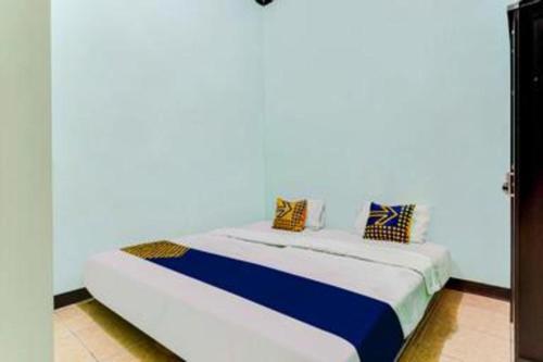 a bed in a room with a white wall at SPOT ON 91159 Kost Putrana Syariah in Bandung