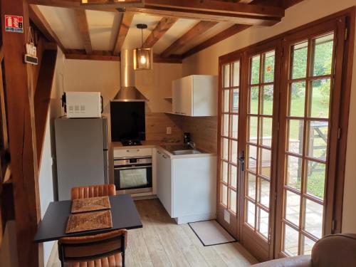 eine Küche mit einem Kühlschrank und einem Tisch mit Stühlen in der Unterkunft Domaine le Manège - Gite Le Phare - près d'Etretat in Sainte-Marie-au-Bosc
