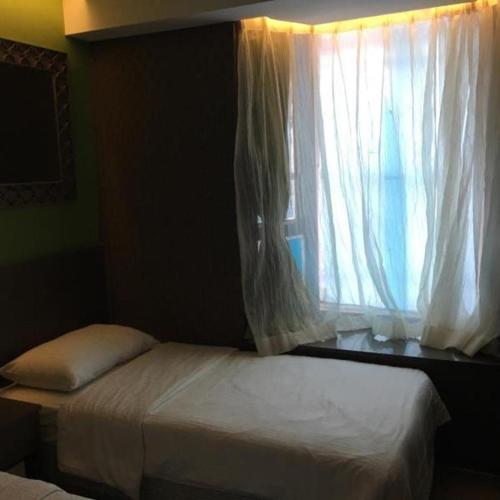 a bedroom with a bed and a window with curtains at Largos Hotel in Hong Kong