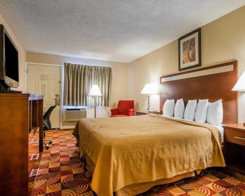 a hotel room with a large bed and a red chair at Quality Inn Redding near I-5 in Redding