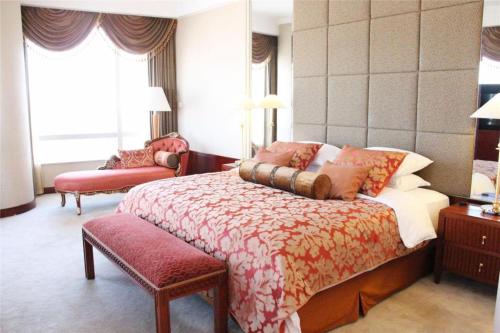 a bedroom with a king sized bed with a red seat at Kai Wah Plaza International Hotel in Kunming