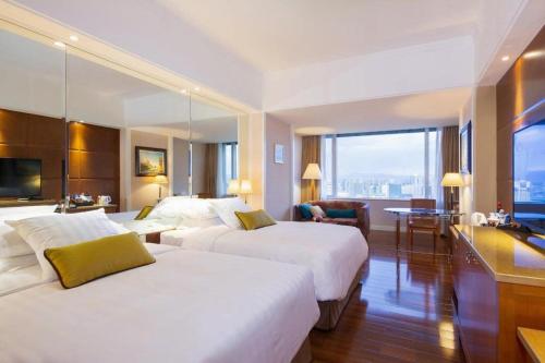 a hotel room with two beds and a desk at Kai Wah Plaza International Hotel in Kunming