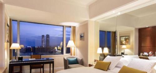 a bedroom with a bed and a desk and a large window at Kai Wah Plaza International Hotel in Kunming