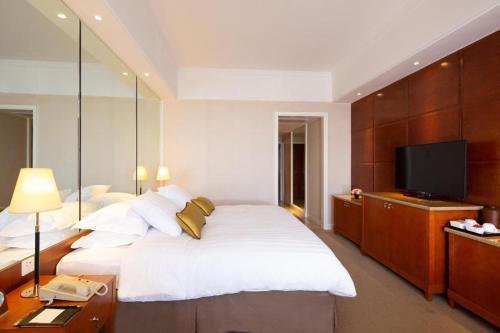 a bedroom with a large white bed and a flat screen tv at Kai Wah Plaza International Hotel in Kunming