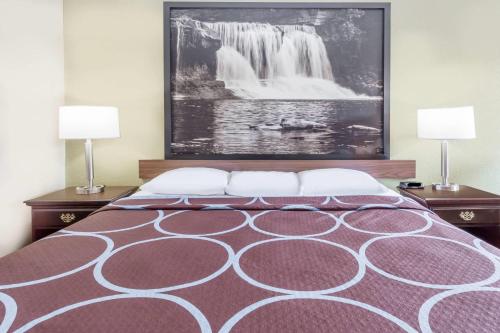 a bedroom with a bed with a painting on the wall at Super 8 by Wyndham Logansport in Logansport