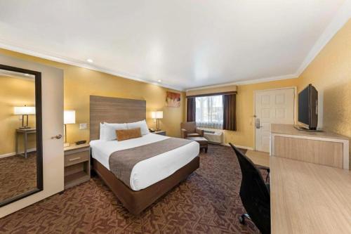 a hotel room with a bed and a flat screen tv at Best Western Hanford Inn in Hanford