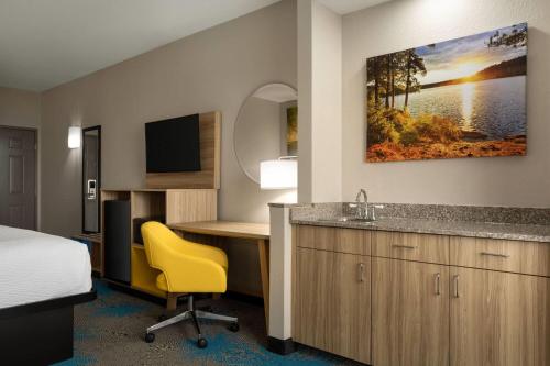 a hotel room with a bed and a desk and a sink at Days Inn & Suites by Wyndham Prattville-Montgomery in Prattville