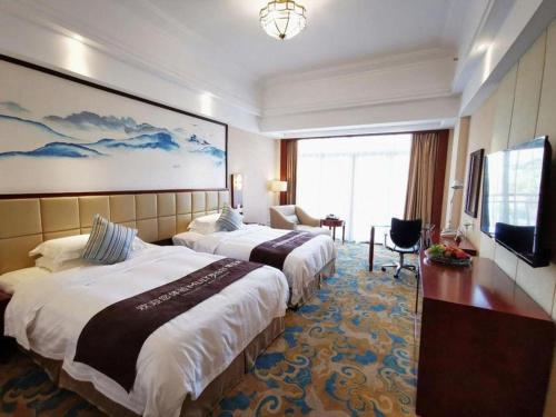 a hotel room with two beds and a flat screen tv at Yangshuo Greenlotus Hotel in Yangshuo