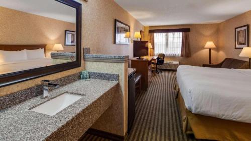 a hotel room with a bed and a bathroom with a sink at Best Western Rama Inn in Ephrata