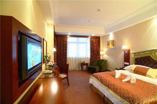 a hotel room with a bed and a flat screen tv at Yangshuo Greenlotus Hotel in Yangshuo