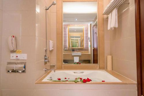a bathroom with a bath tub with a mirror at Yangshuo Greenlotus Hotel in Yangshuo