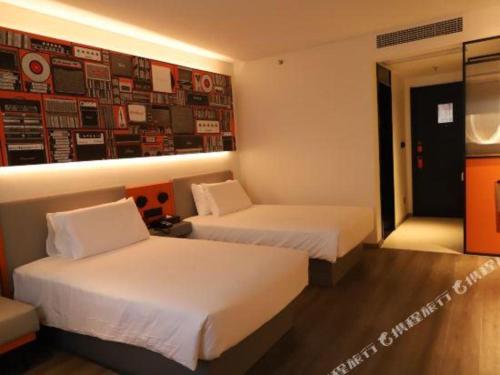 a hotel room with two beds and a painting on the wall at ibis Dongguan Dongcheng in Dongguan