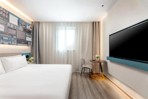 a hotel room with a bed and a flat screen tv at ibis Dongguan Dongcheng in Dongguan