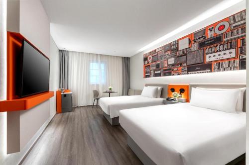 a hotel room with two beds and a flat screen tv at ibis Dongguan Dongcheng in Dongguan