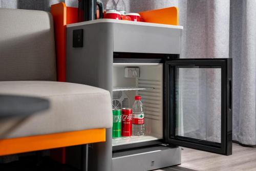 a small refrigerator with a door open with drinks in it at ibis Dongguan Dongcheng in Dongguan