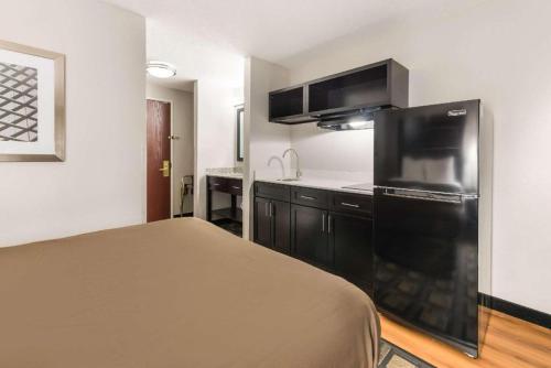 a small kitchen with a black refrigerator in a room at Suburban Studios Mason Hwy 42 in Mason