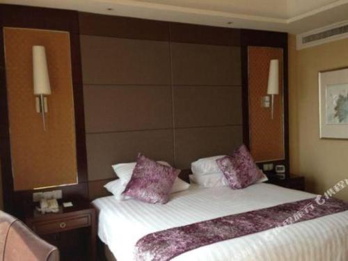a hotel room with a large bed with purple pillows at Gaosu New Century Hotel International Anhui in Hefei
