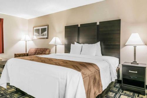 a hotel room with a large bed and a chair at Suburban Studios Mason Hwy 42 in Mason