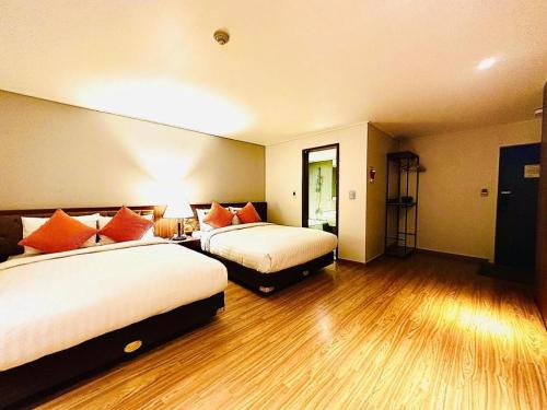 a hotel room with two beds and wooden floors at Hotel One Byeonsan in Buan