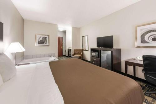 a hotel room with a large bed and a desk at Suburban Studios Mason Hwy 42 in Mason