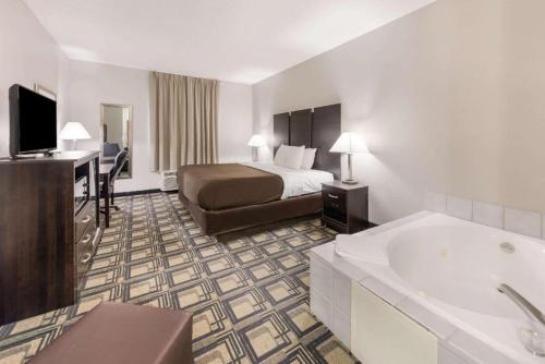 a hotel room with a bed and a bath tub at Suburban Studios Mason Hwy 42 in Mason