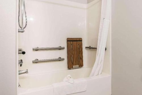 a bathroom with a bath tub with a wooden shower curtain at Suburban Studios Mason Hwy 42 in Mason