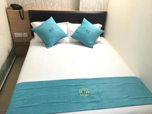 a bed with blue and white pillows on it at 85 Beach Garden Hotel in Singapore