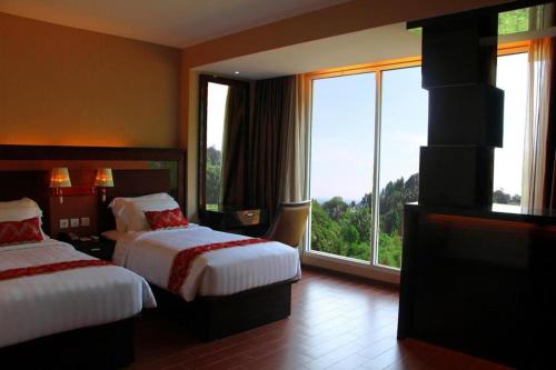 a hotel room with two beds and a large window at The Belagri Hotel and Convention in Sorong