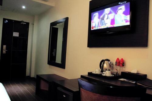 a room with a television on a wall with a table at The Belagri Hotel and Convention in Sorong