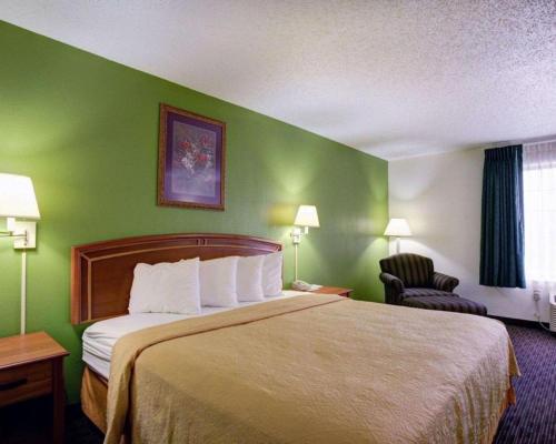 a hotel room with a bed and a green wall at Quality Inn & Suites Airport in Austin