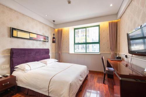 a bedroom with a bed and a desk and a television at Yiwu Baiheng Hotel in Yiwu
