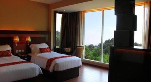 a hotel room with two beds and a large window at The Belagri Hotel and Convention in Sorong