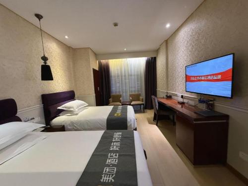 a hotel room with two beds and a flat screen tv at Yiwu Baiheng Hotel in Yiwu