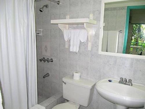 a bathroom with a toilet and a sink and a mirror at Gold Nugget Hotel in Negril