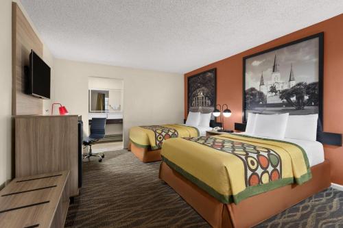 ein Hotelzimmer mit zwei Betten und einem Flachbildfernseher in der Unterkunft Super 8 by Wyndham New Orleans in New Orleans