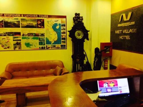 a living room with a couch and a clock at Viet Village Hotel in Hanoi