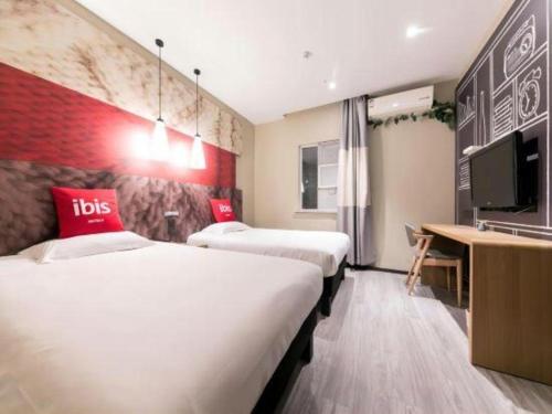 a hotel room with two beds and a flat screen tv at Ibis Nantong Qingnian in Nantong