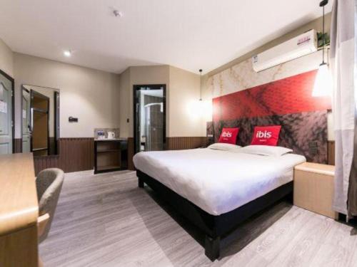 a hotel room with a large bed with red pillows at Ibis Nantong Qingnian in Nantong