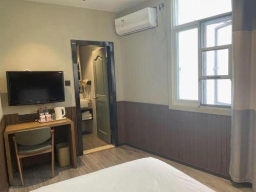 a room with a bed and a desk and a television at Ibis Nantong Qingnian in Nantong