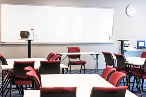 an empty classroom with tables and chairs and a whiteboard at Scandic Uplandia in Uppsala