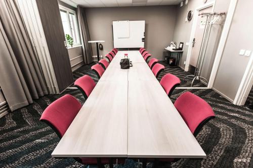 a long table with red chairs in a conference room at Scandic Uplandia in Uppsala