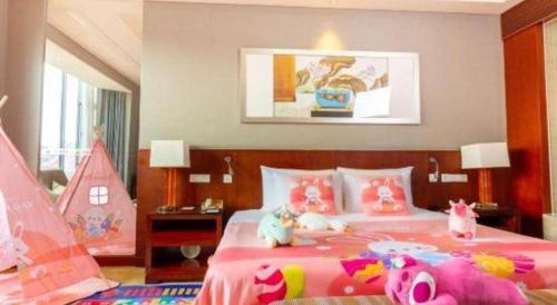 a bedroom with a large pink bed with stuffed animals on it at Quanzhou Guest House Hotel in Quanzhou