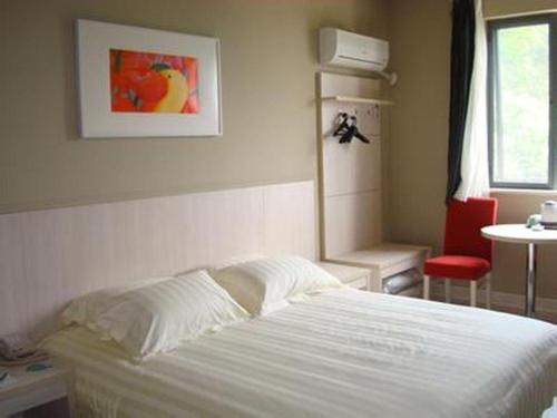a bedroom with a white bed and a red chair at Jinjiang Inn Select Shanghai International Tourism and Resorts Zone Chuansha Road Subway Station in Shanghai