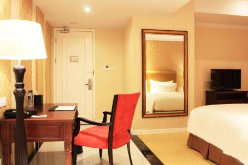 a bedroom with a desk and a bed and a mirror at Adimulia Hotel Medan in Medan