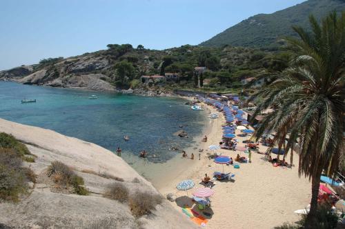 a beach with a bunch of people in the water at Hotel Castello Monticello in Giglio Porto