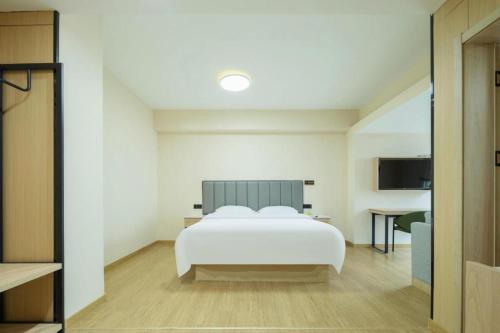 a bedroom with a white bed and a desk at GreenTree Inn Weihai Liugongdao Wharf Qingdao North Road Express Hotel in Weihai