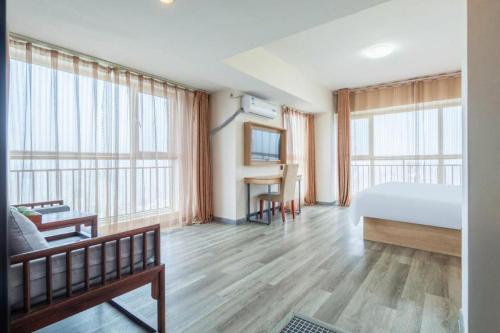 a hotel room with a bed and a desk and windows at GreenTree Inn Weihai Liugongdao Wharf Qingdao North Road Express Hotel in Weihai