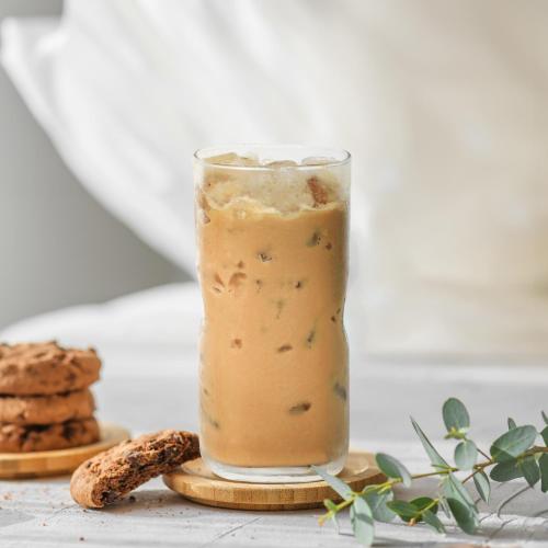 a glass of iced coffee on a table with cookies at Swan Boutique Hotel in Ho Chi Minh City