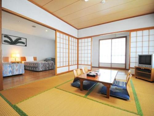 a living room with a table and chairs and a bedroom at Hotel Thida No Sato in Miyako Island