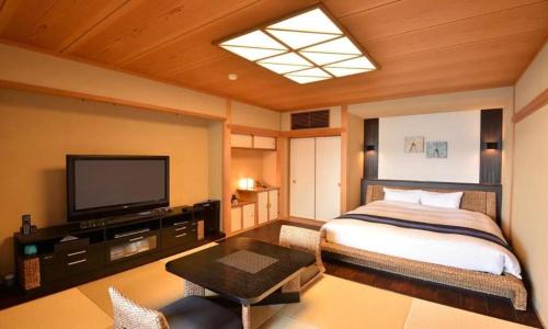 a bedroom with a bed and a flat screen tv at Luxury Wa Hotel Kaze No Kaori in Ito
